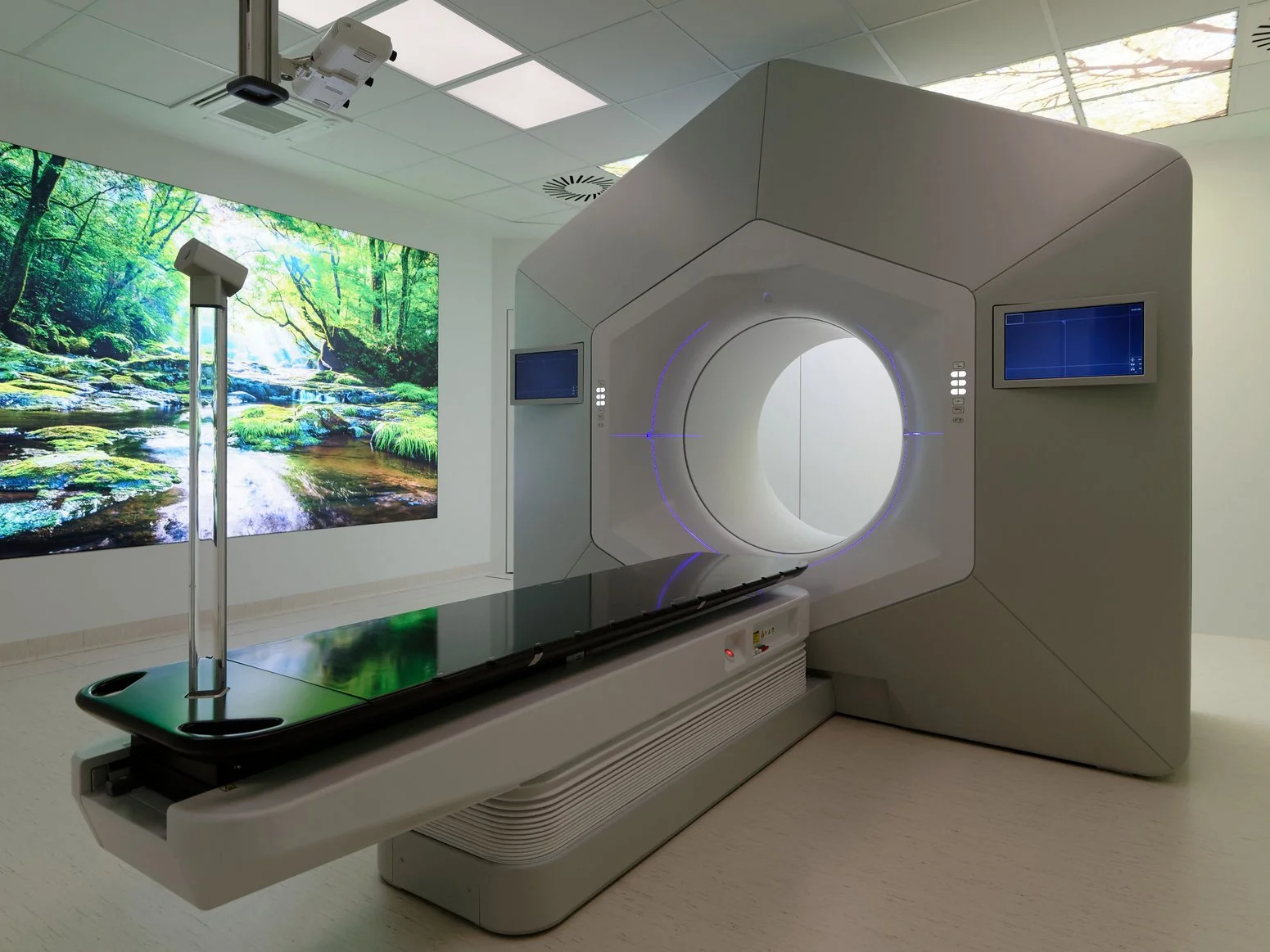 Moderner Bestrahlungsraum mit großem Therapiegerät und beruhigender Naturprojektion an der Wand