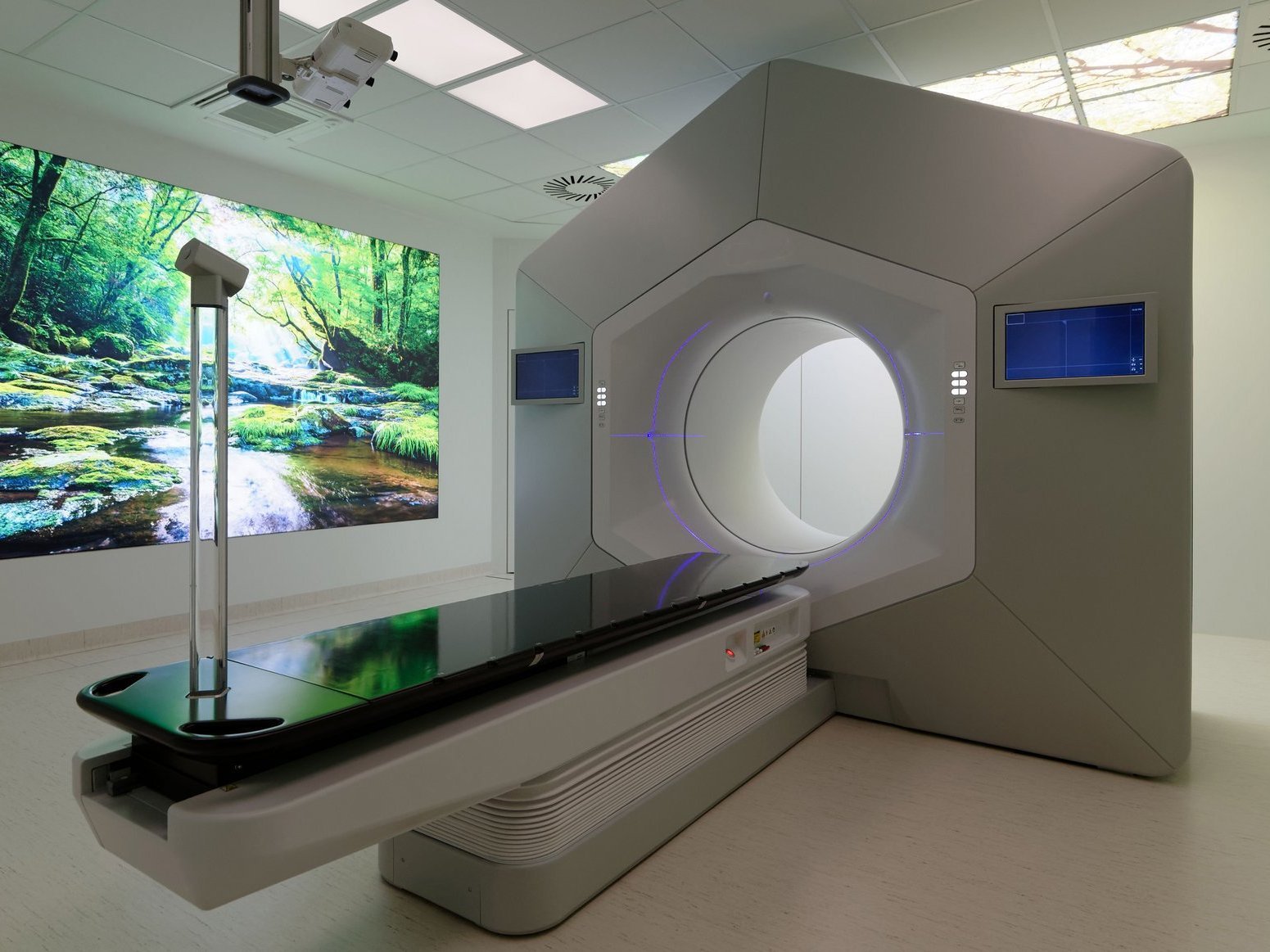 Moderner Bestrahlungsraum mit großem Therapiegerät und beruhigender Naturprojektion an der Wand