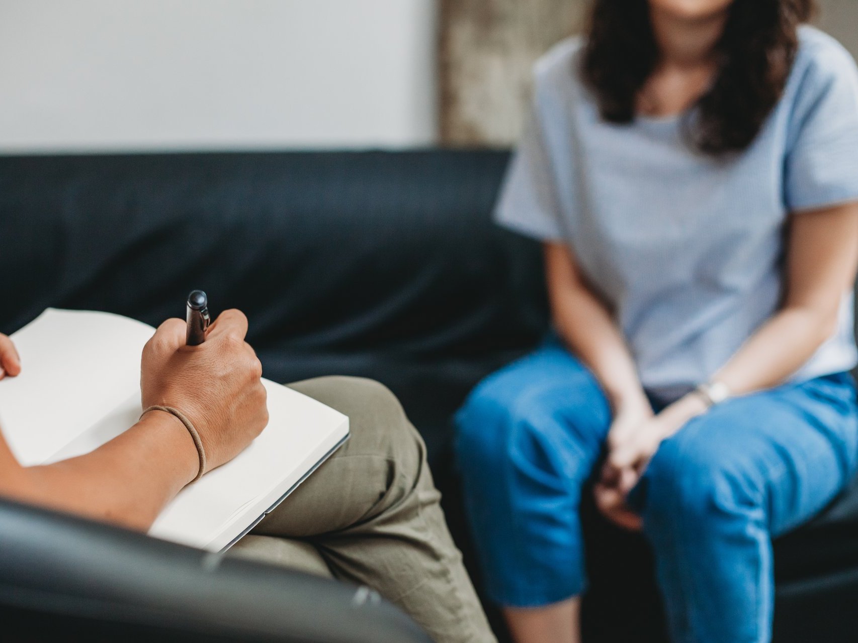 Psychotherapy session, woman talking to his psychologist in the Psychologisches Gespräch: Eine Frau sitzt auf einem Sofa, die Therapeutin macht sich Notizen